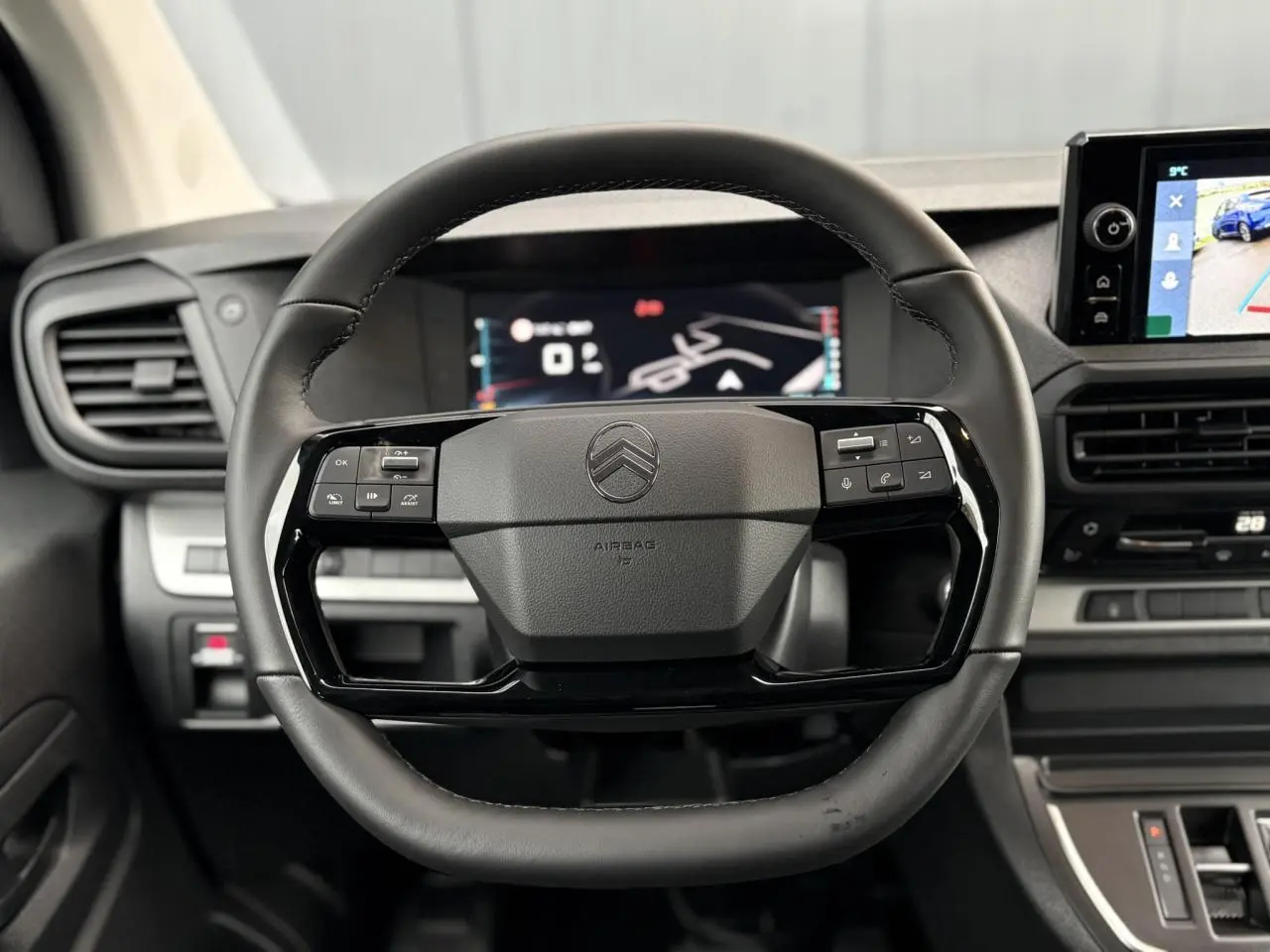 Vue rapprochée du volant cuir noir du Citroën Jumpy 2025 avec commandes intégrées et tableau de bord numérique.