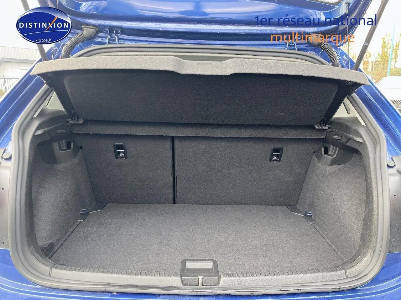 Coffre ouvert vu de l'arrière d'une Volkswagen Polo bleu récif, montrant un espace de rangement propre et spacieux.