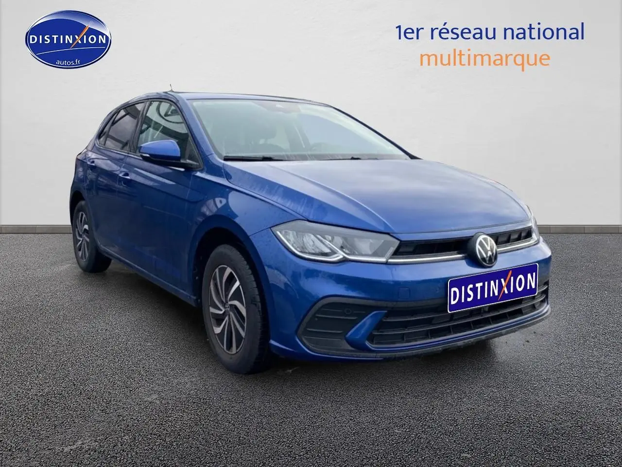 Volkswagen Polo 1.0 TSI bleu récif en vue 3/4 avant droit sur sol gris, avec calandre et phares LED visibles.
