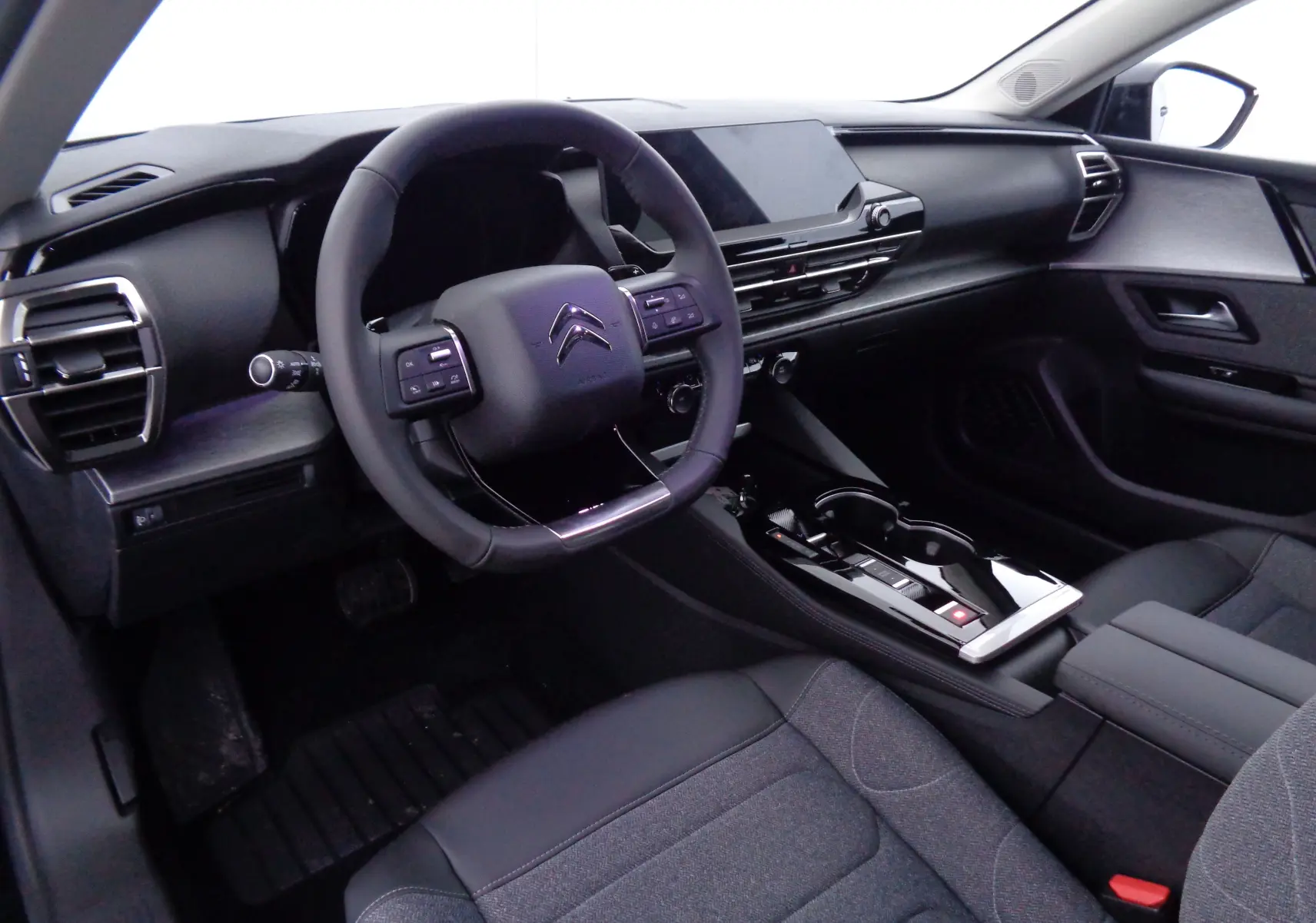 Intérieur noir du Citroën C5 X 2023 vu côté conducteur, avec volant multifonction et console centrale moderne.