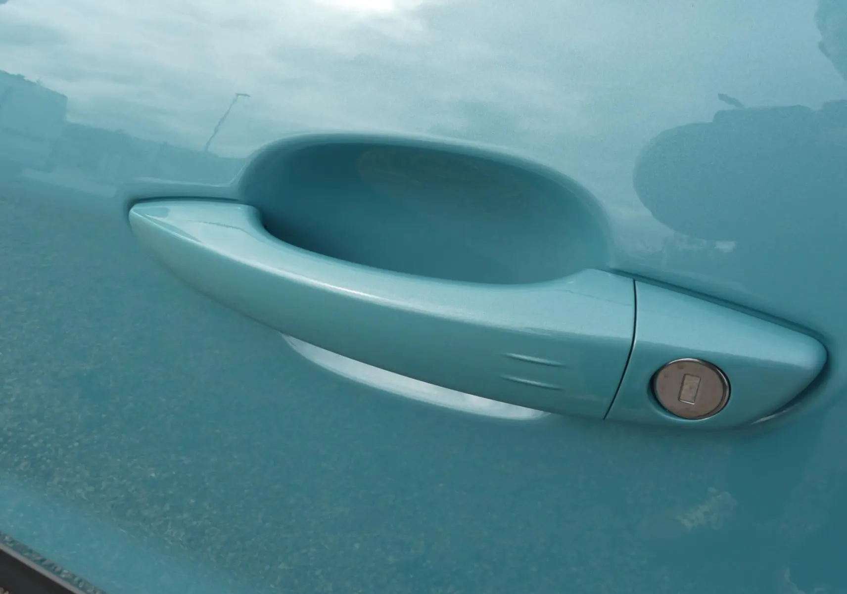 Poignée de porte côté droit bleu métallisé d'un Jeep Avenger 2024 avec serrure intégrée visible.