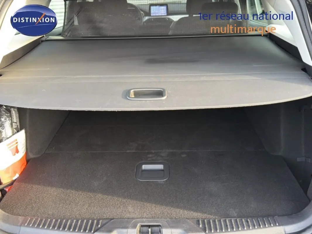 Coffre ouvert vu de l'arrière d'une Ford Focus SW noire, avec cache-bagages et intérieur sombre.