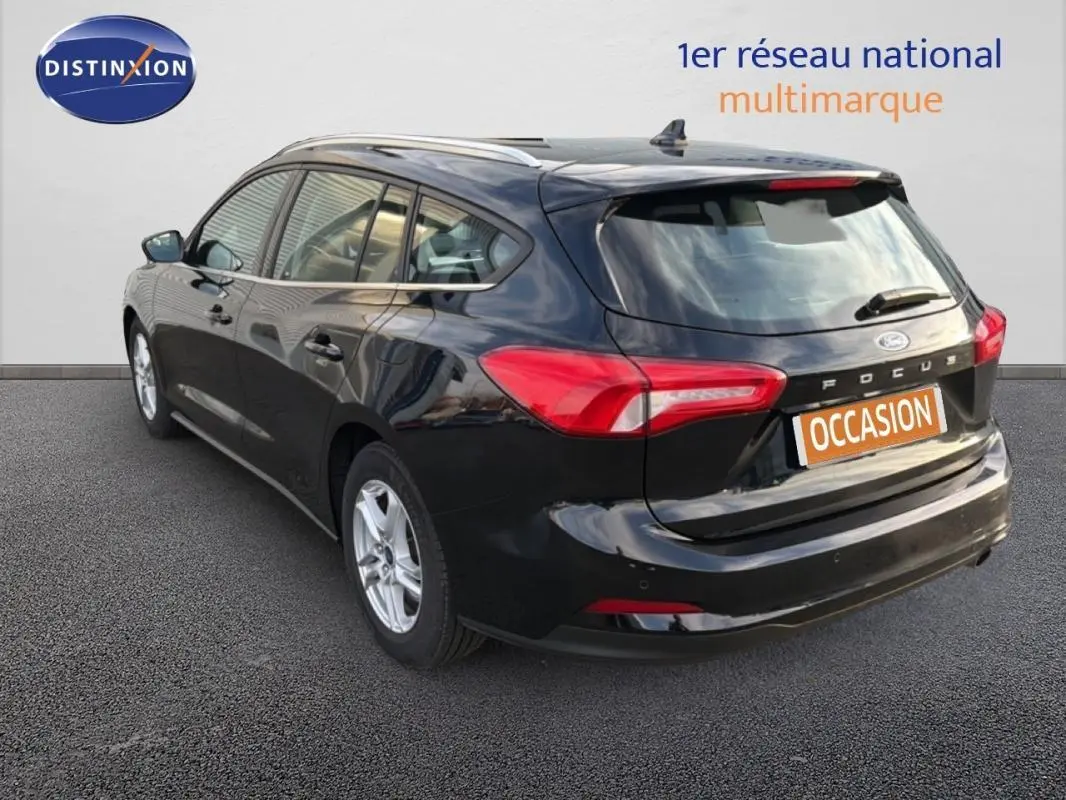 Vue 3/4 arrière droite d'une Ford Focus SW noire de 2019 avec barres de toit et jantes alliage 16 pouces.