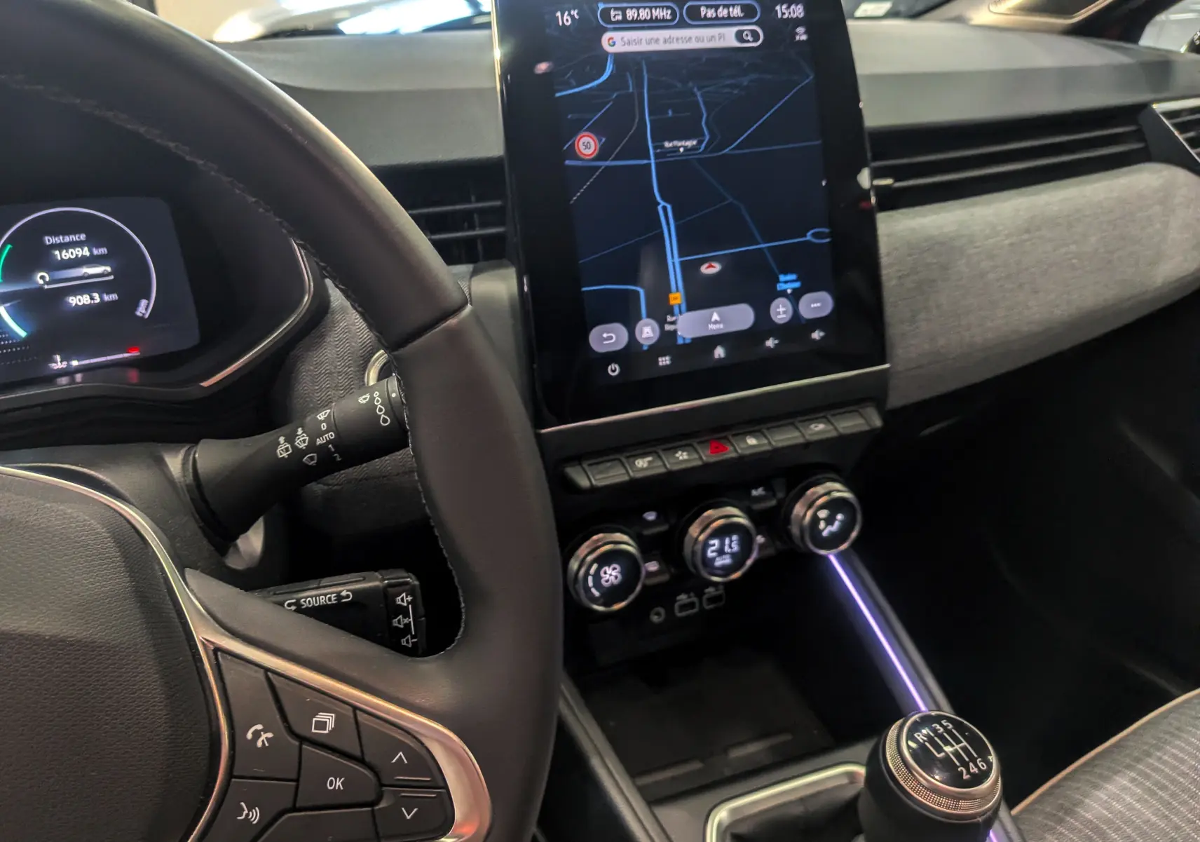 Vue intérieure centrée sur le tableau de bord et la console centrale de la Renault Clio V avec écran tactile et levier de vitesses manuel.