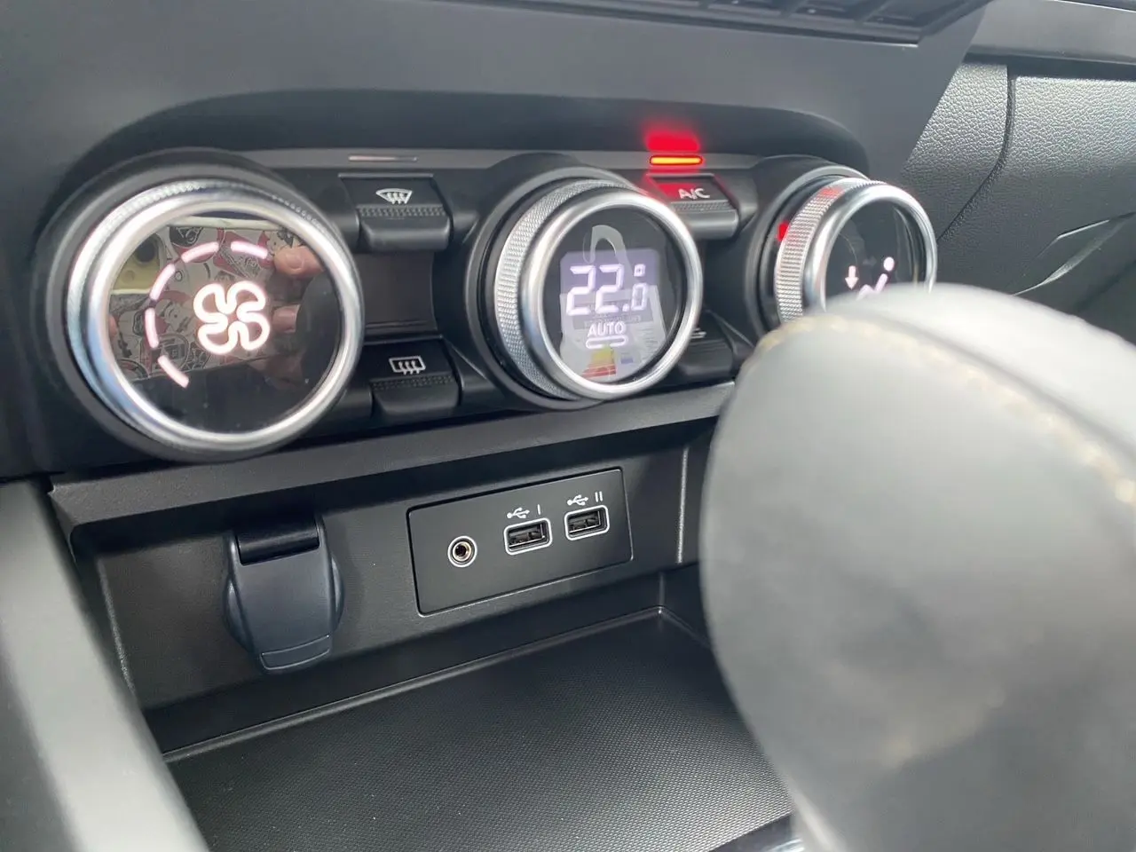 Gros plan sur la console centrale du Renault Arkana 2024 noir, montrant les commandes de climatisation et ports USB.