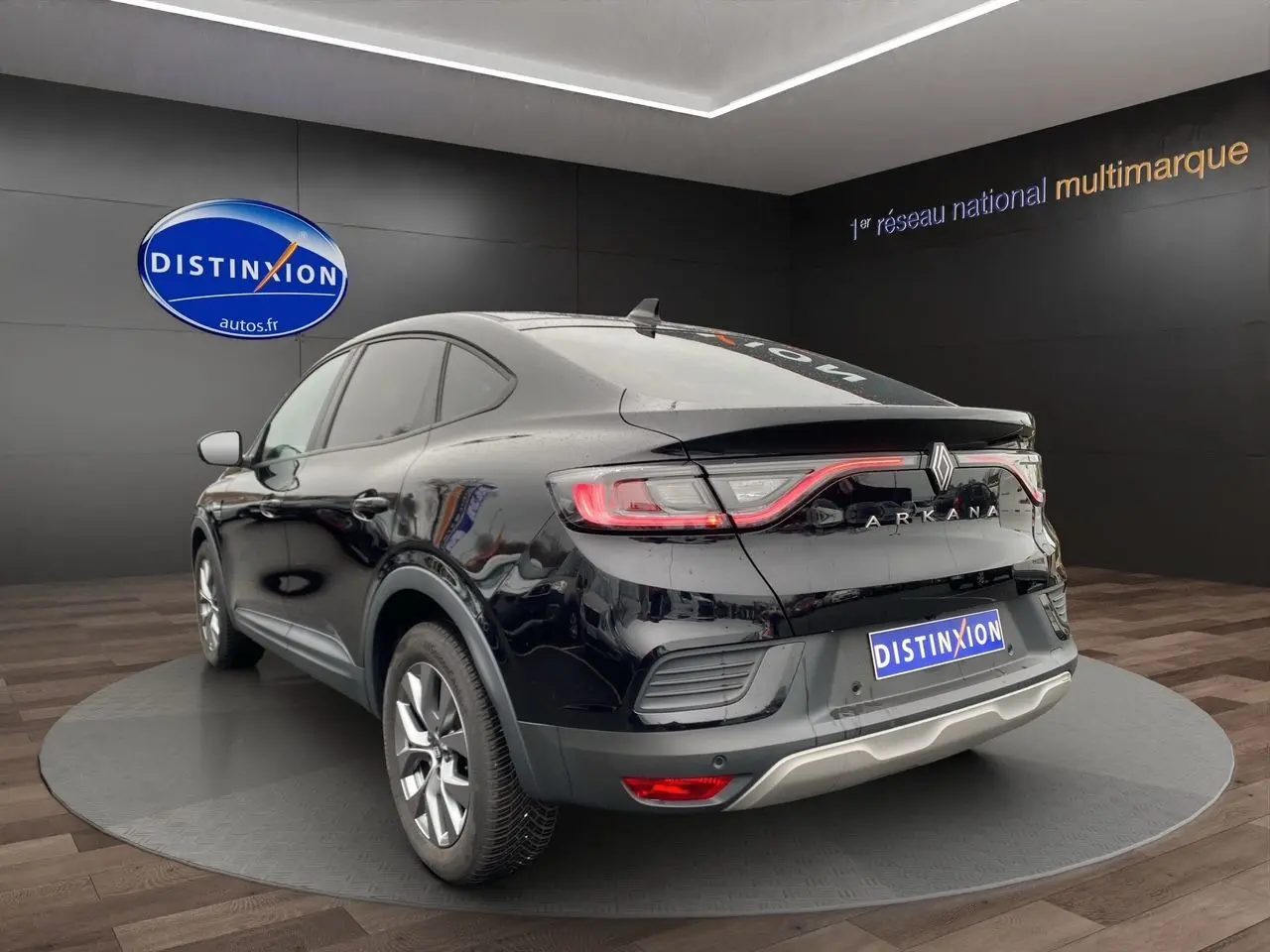 Vue 3/4 arrière droite du Renault Arkana noir 2024 avec feux arrière LED et logo distinctif sur fond showroom.