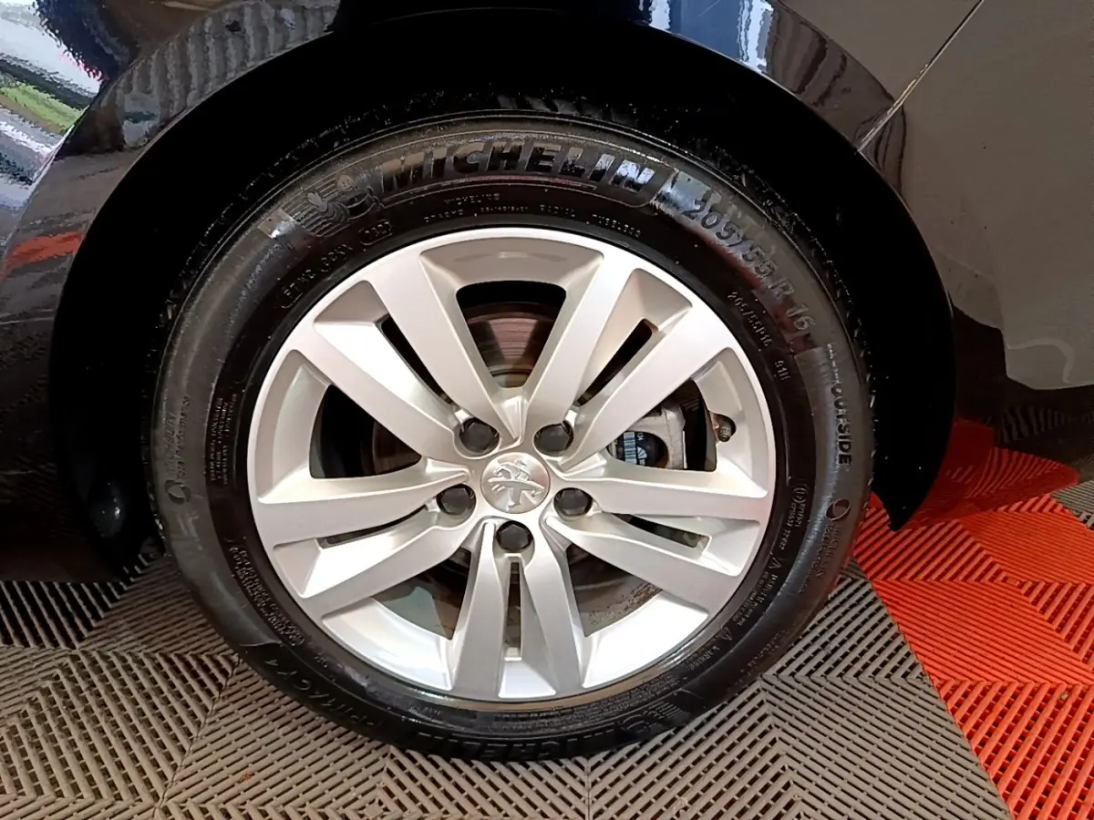 Gros plan sur la roue avant droite avec jante argentée et pneu Michelin sur Peugeot 308 noir.