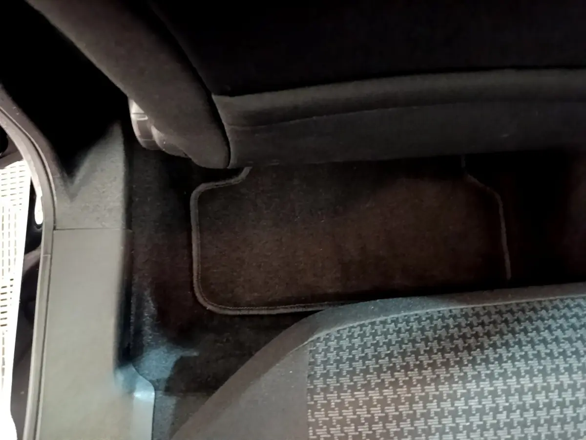 Plancher arrière côté droit avec tapis noir et partie inférieure du siège arrière d’une Peugeot 308 noire 2020.