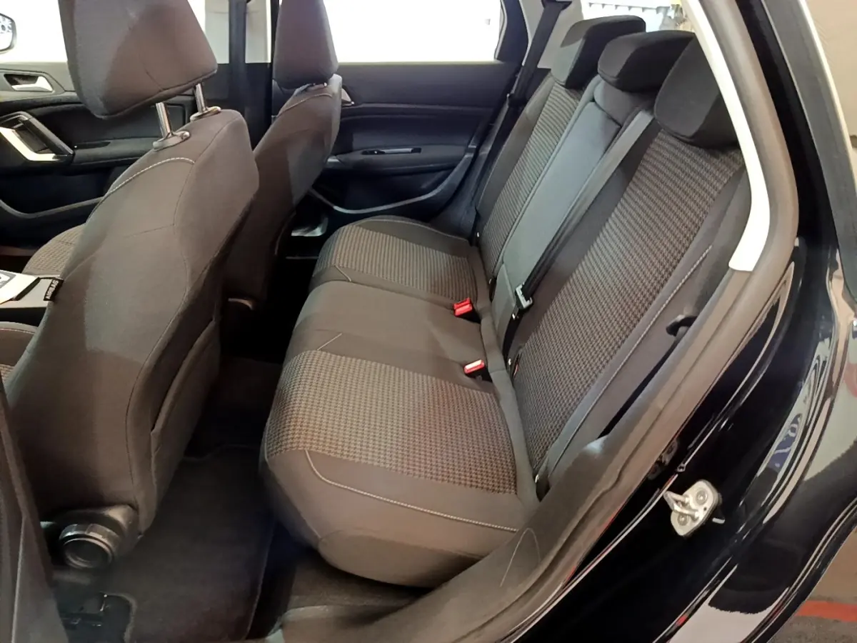 Vue intérieure côté droit montrant la banquette arrière grise et les sièges avant d'une Peugeot 308 noire de 2020.
