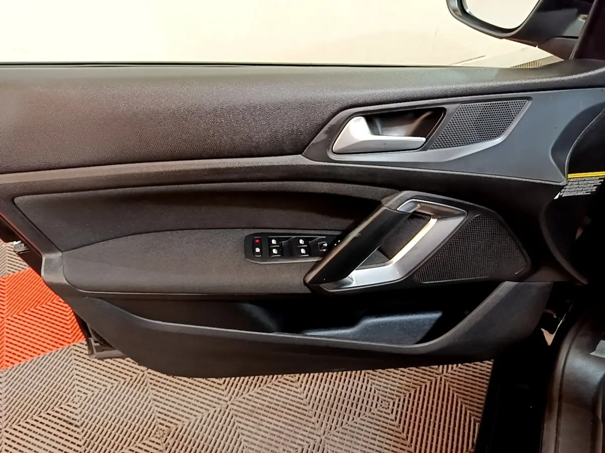 Vue intérieure du panneau de porte avant gauche de la Peugeot 308 noire avec commandes électriques et poignée argentée.