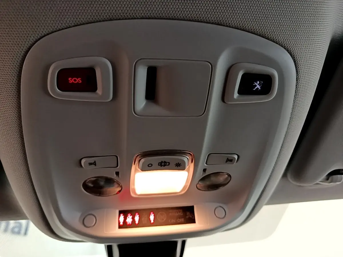 Vue intérieure du plafonnier avant de la Peugeot 308 noire, avec éclairage et boutons SOS et assistance visibles.