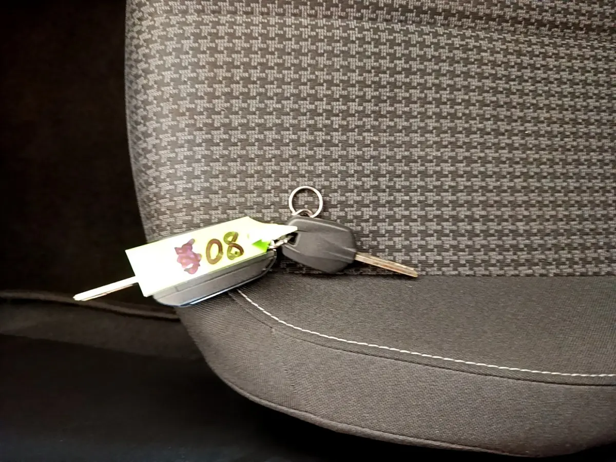 Clé de voiture posée sur le siège avant tissu gris foncé à motifs, intérieur du Peugeot 308 noir 2020.