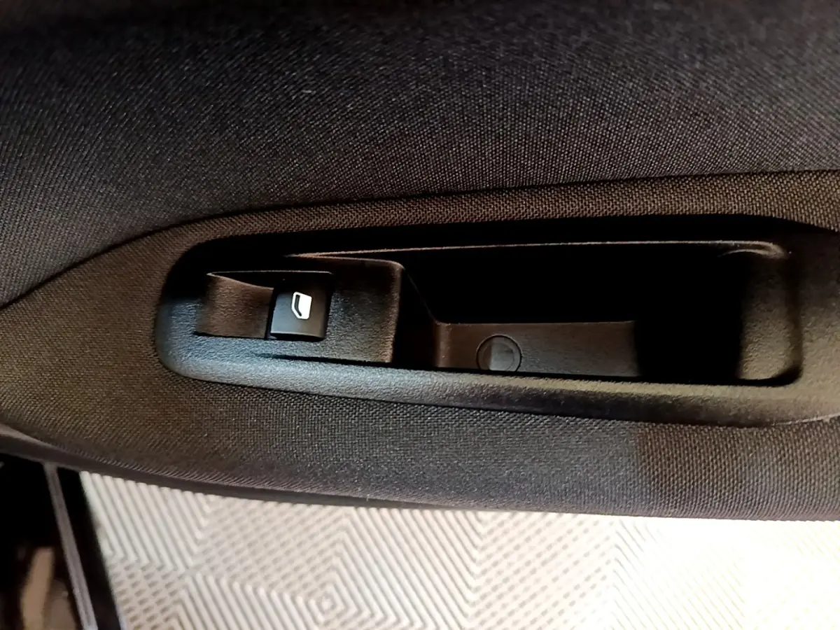 Détail de la commande d’ouverture de vitre électrique sur la porte intérieure d’une Peugeot 308 noire de 2020.