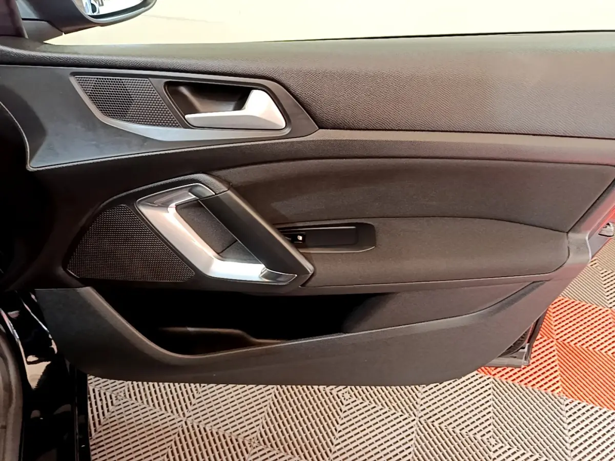 Vue intérieure du panneau de porte côté gauche noir de la Peugeot 308 Active Business 2020 avec poignée argentée.