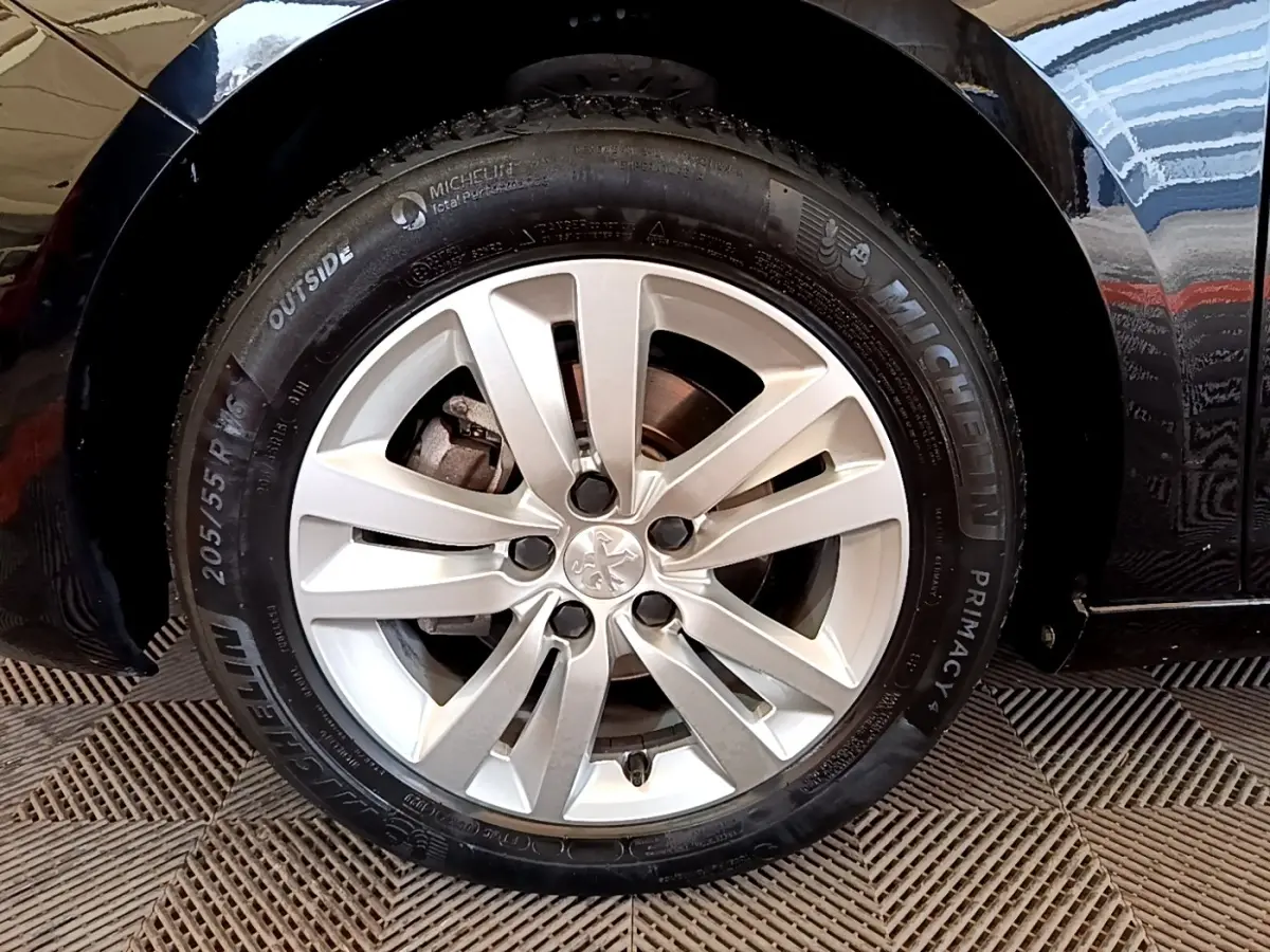 Vue rapprochée sur la roue arrière droite d’une Peugeot 308 noire, avec reflet sur la carrosserie brillante.