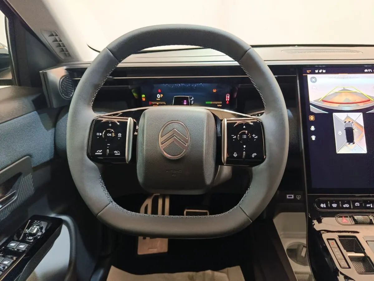 Vue intérieure centrée sur le volant cuir noir de la Citroën C5 Hybride avec écran tactile et affichage multifonctions.