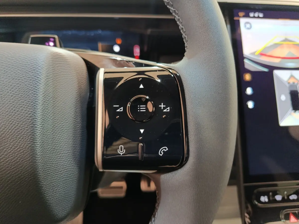 Gros plan sur la commande multifonctions noire à droite du volant cuir gris du Citroën C5 Hybride 2026, avec écran tactile en arrière-plan.