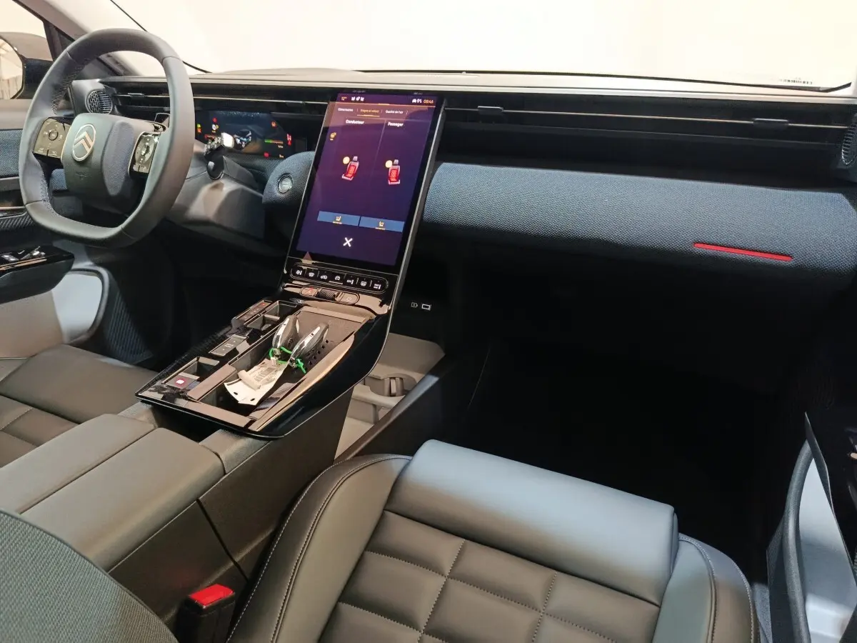 Intérieur avant droit de la Citroën C5 Hybride 2026, tableau de bord moderne avec écran tactile vertical et volant cuir noir.