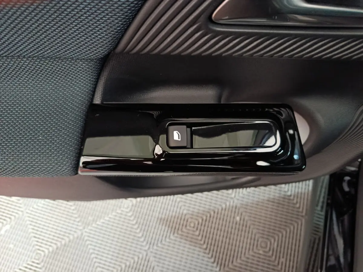 Gros plan sur le bouton de déverrouillage de porte noir brillant côté intérieur d'une Citroën C5 Hybride 2026.