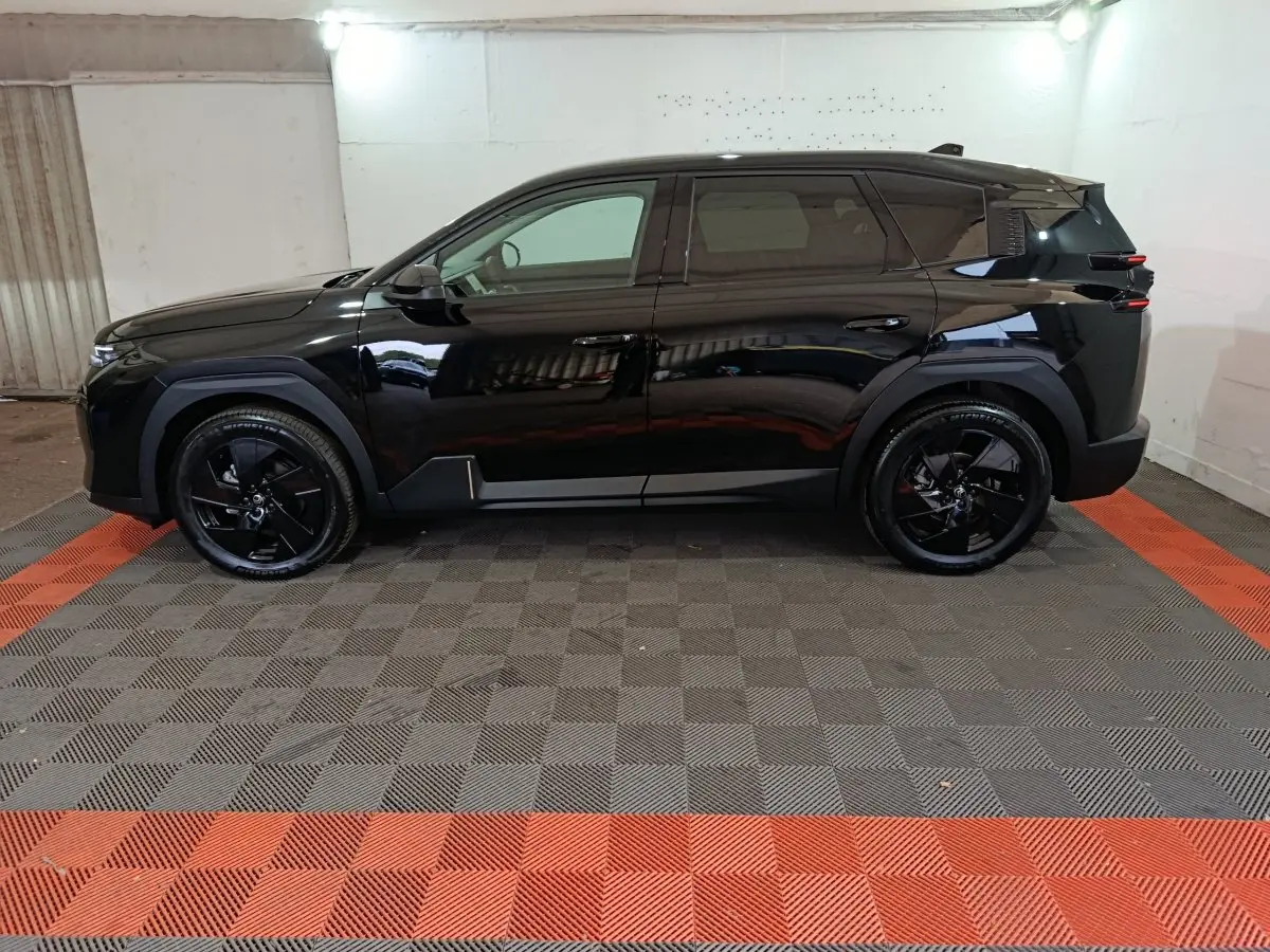 Vue de profil côté gauche d'un Citroën C5 Hybride noir 2026 avec jantes noires et lignes modernes marquées.