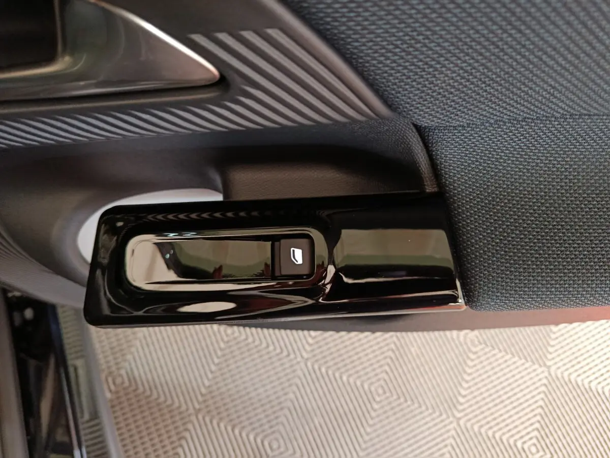 Détail de la commande électrique de lève-vitre sur la porte intérieure côté gauche d'une Citroën C5 hybride noire.