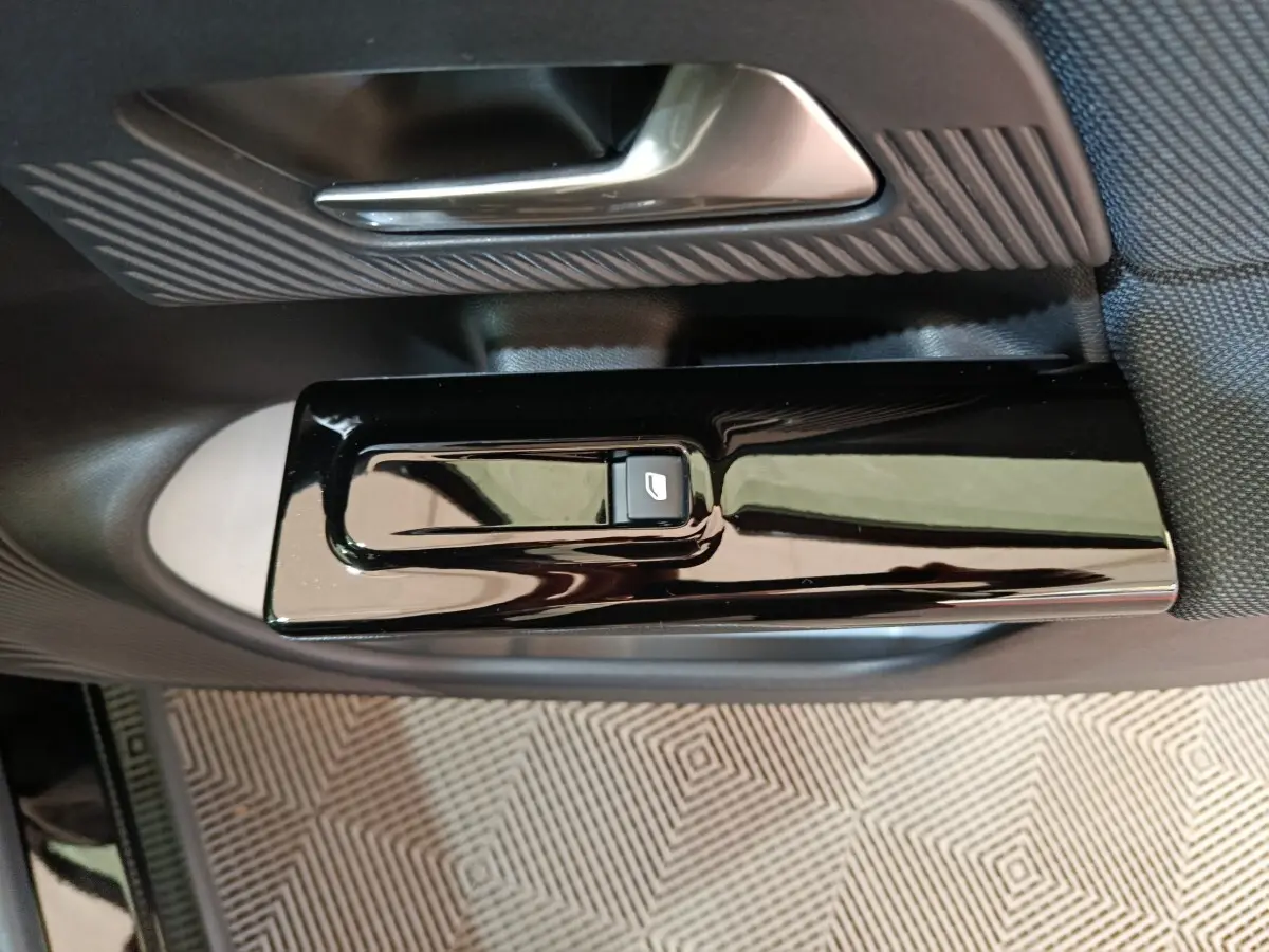 Gros plan sur la commande de lève-vitre noir brillant et poignée de porte intérieure du côté gauche d’une Citroën C5 Hybride.