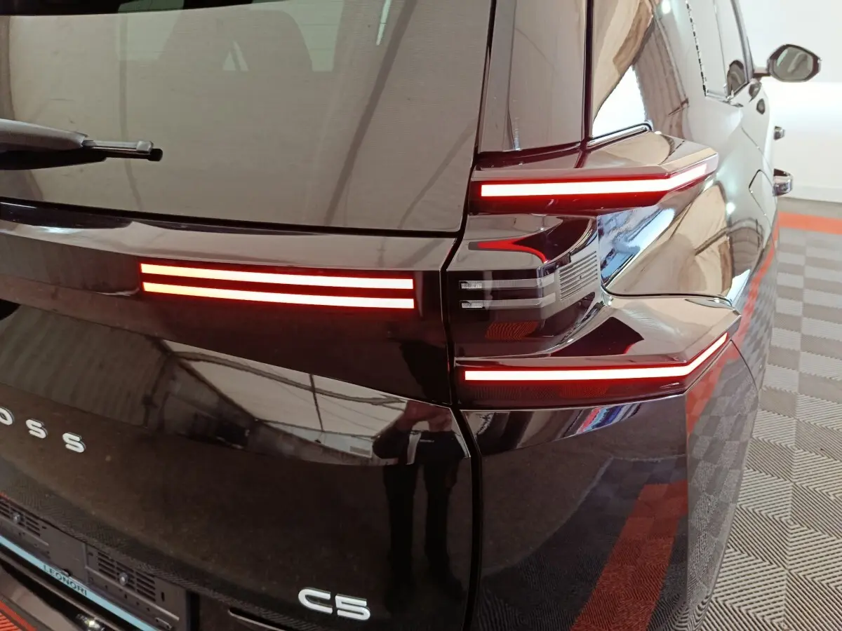 Vue arrière droite d'une Citroën C5 noire 2026 avec feux arrière LED horizontaux distinctifs allumés.
