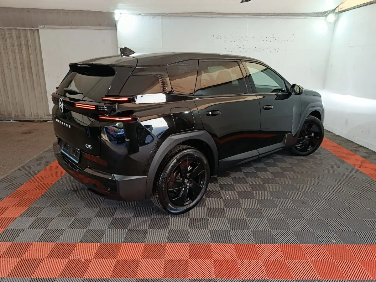 Vue 3/4 arrière droite d'une Citroën C5 noire avec feux arrière LED horizontaux et jantes noires brillantes.