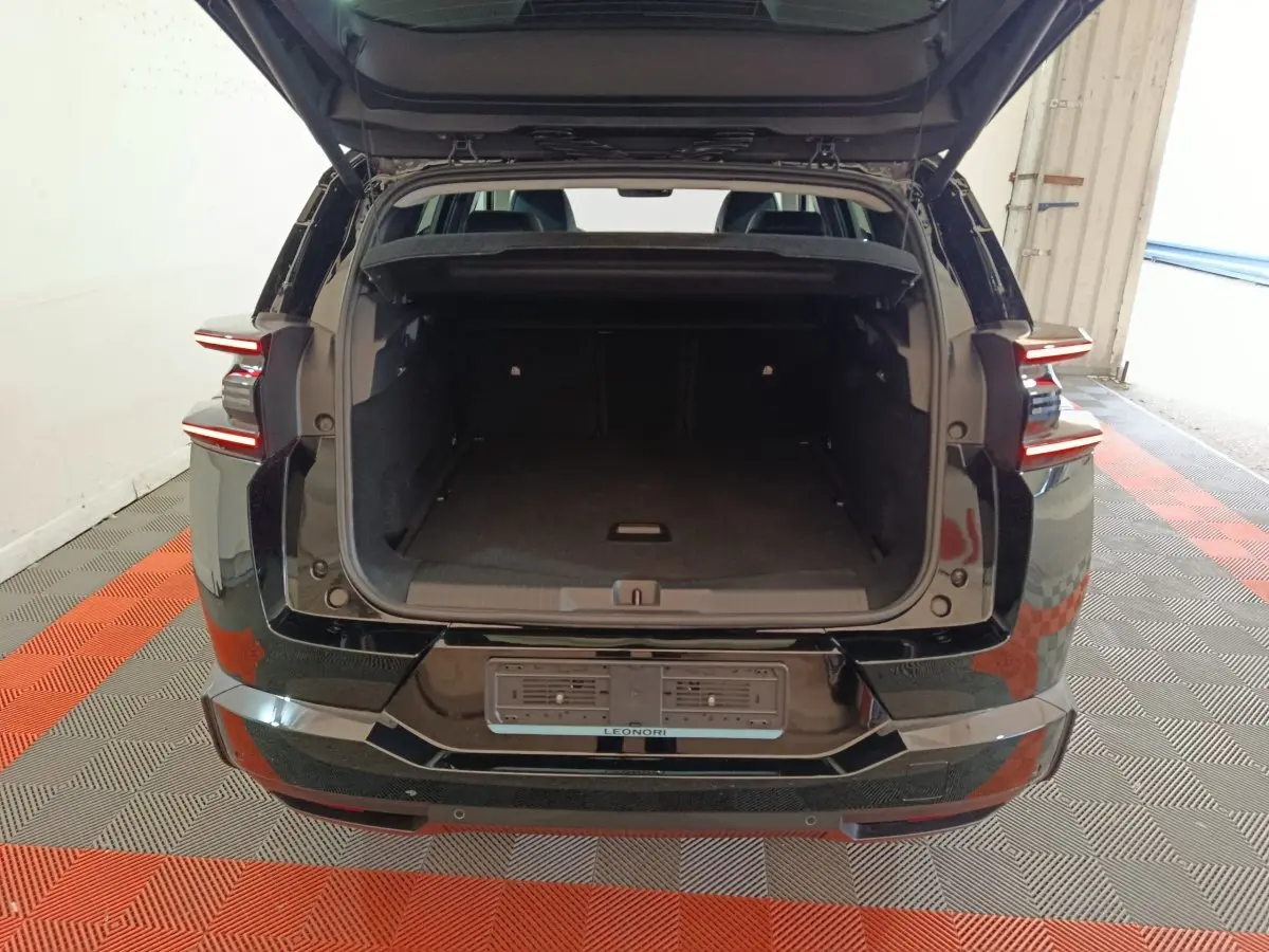 Vue arrière d'un Citroën C5 Hybride noir 2026 avec coffre ouvert et feux arrière LED allumés.