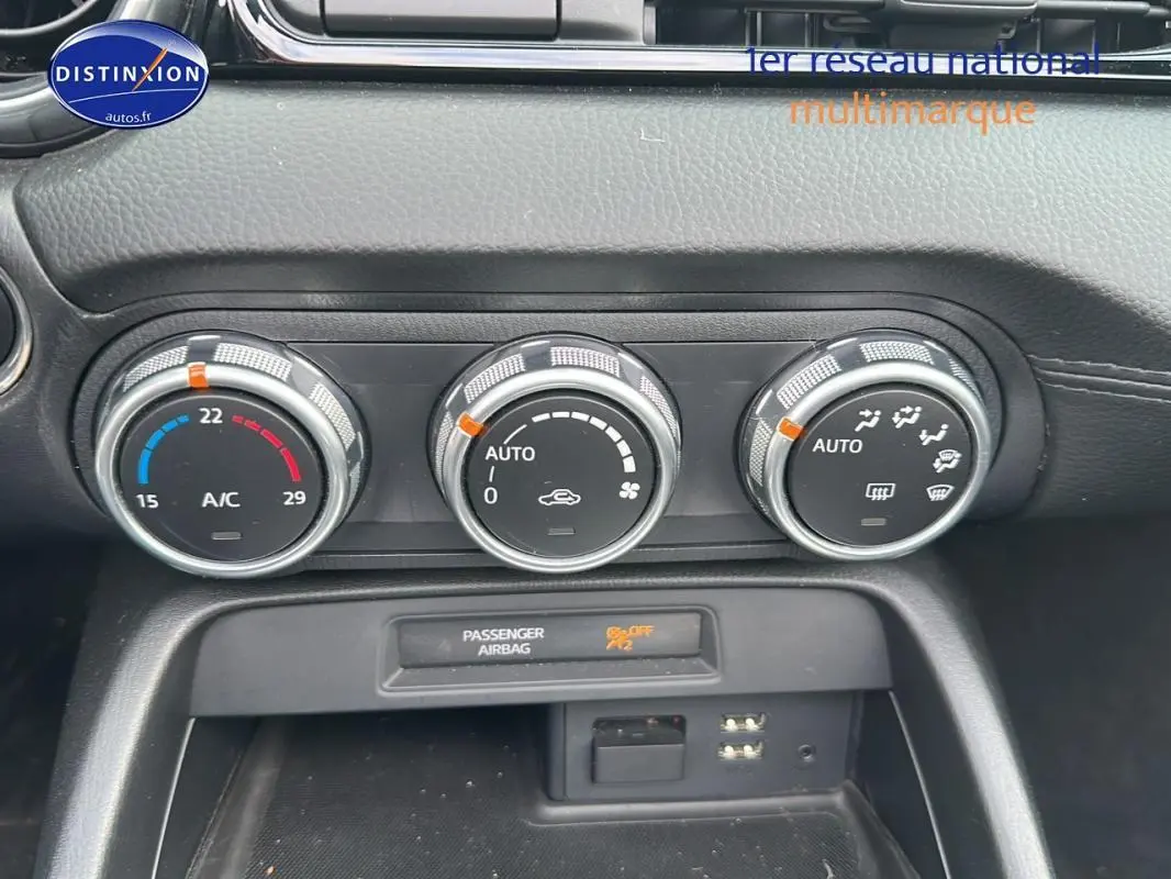 Gros plan sur les commandes de climatisation automatique et l'affichage airbag passager du tableau de bord d'une Fiat 124 Spider Lusso.