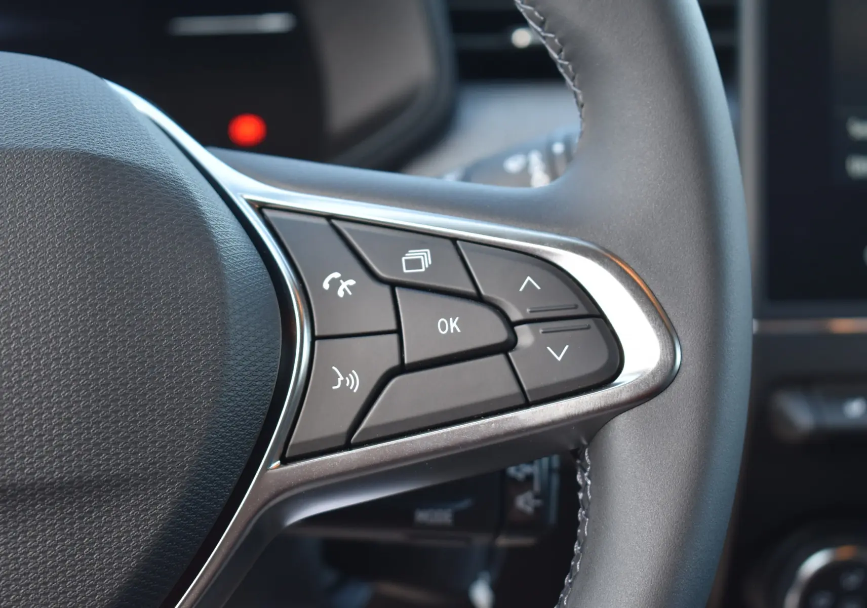 Gros plan sur les commandes multifonctions à droite du volant de la Renault Clio V gris 2024, boutons de navigation et appel.