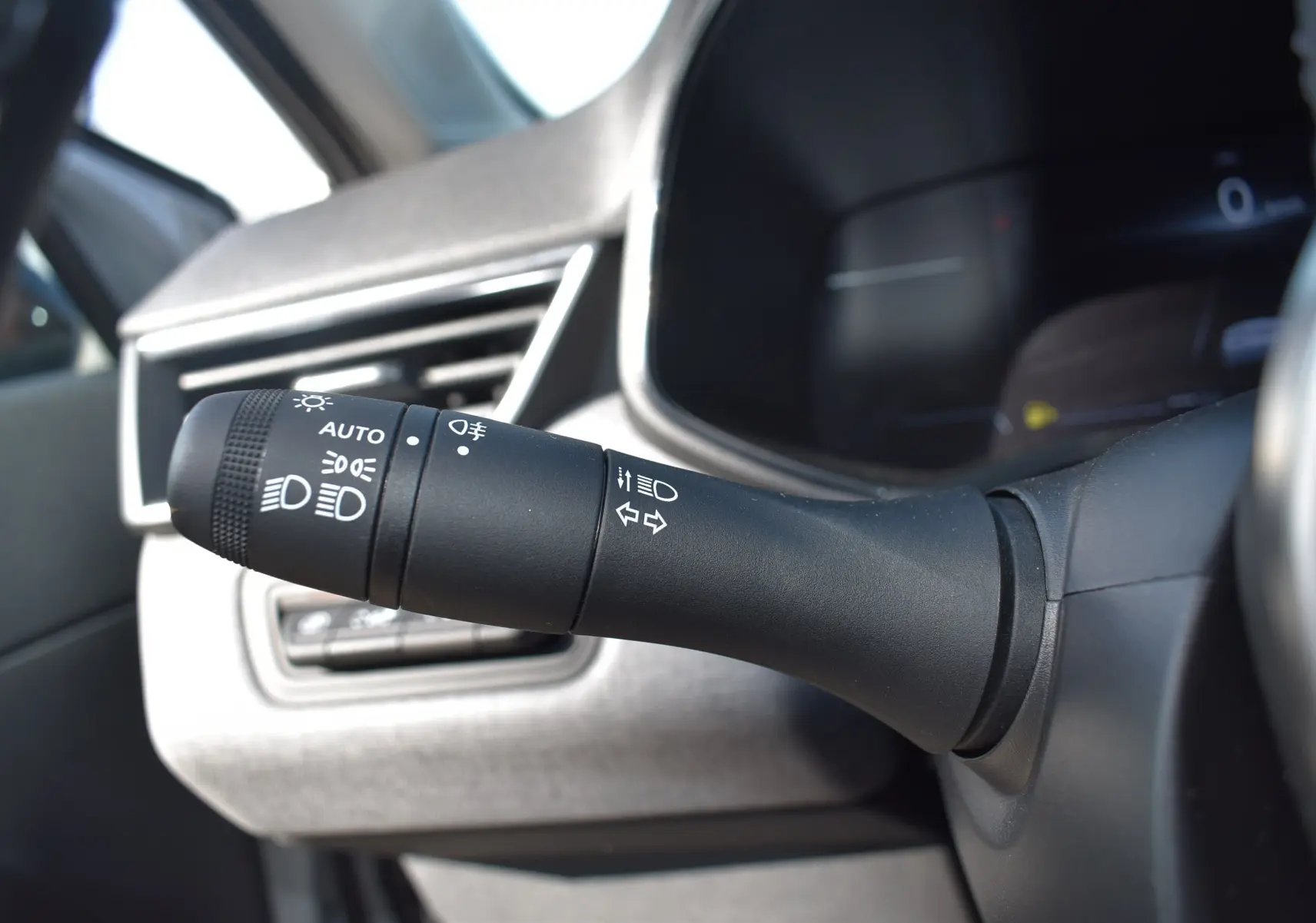 Gros plan sur la commande des phares et clignotants à gauche du volant dans l'habitacle d'une Renault Clio V gris 2024.