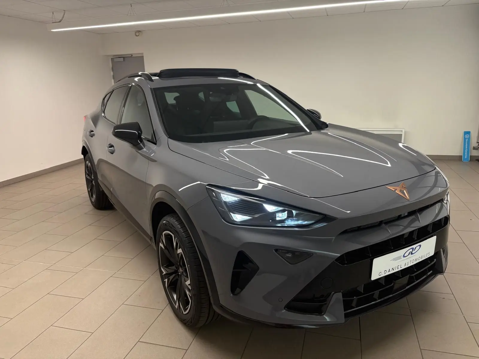 Vue 3/4 avant du CUPRA Formentor 2025 gris Graphène avec toit ouvrant panoramique et jantes alliage 18'' noires.