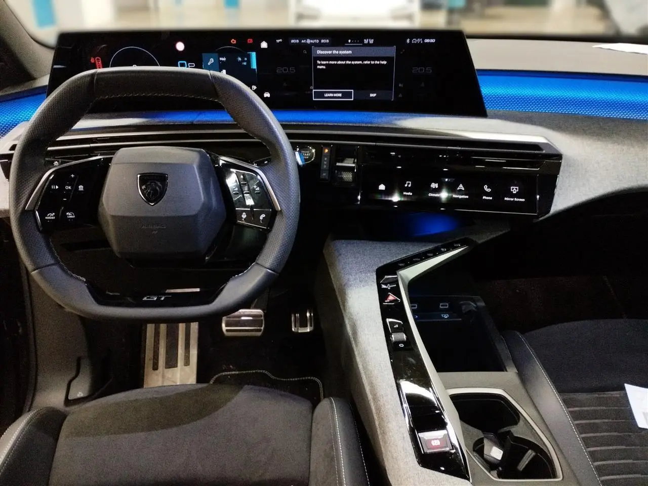 Vue intérieure frontale du Peugeot 3008 Hybrid 145 GT 2025, tableau de bord numérique et volant compact cuir noir avec surpiqûres Iced Clay.