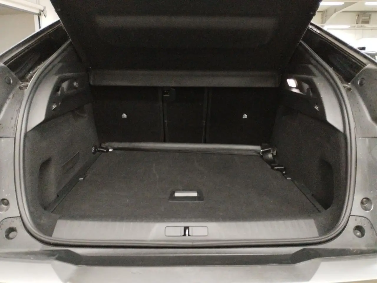 Coffre ouvert vu de l'arrière du Peugeot 3008 Hybrid 145 GT gris Titane avec intérieur noir et plancher modulable.