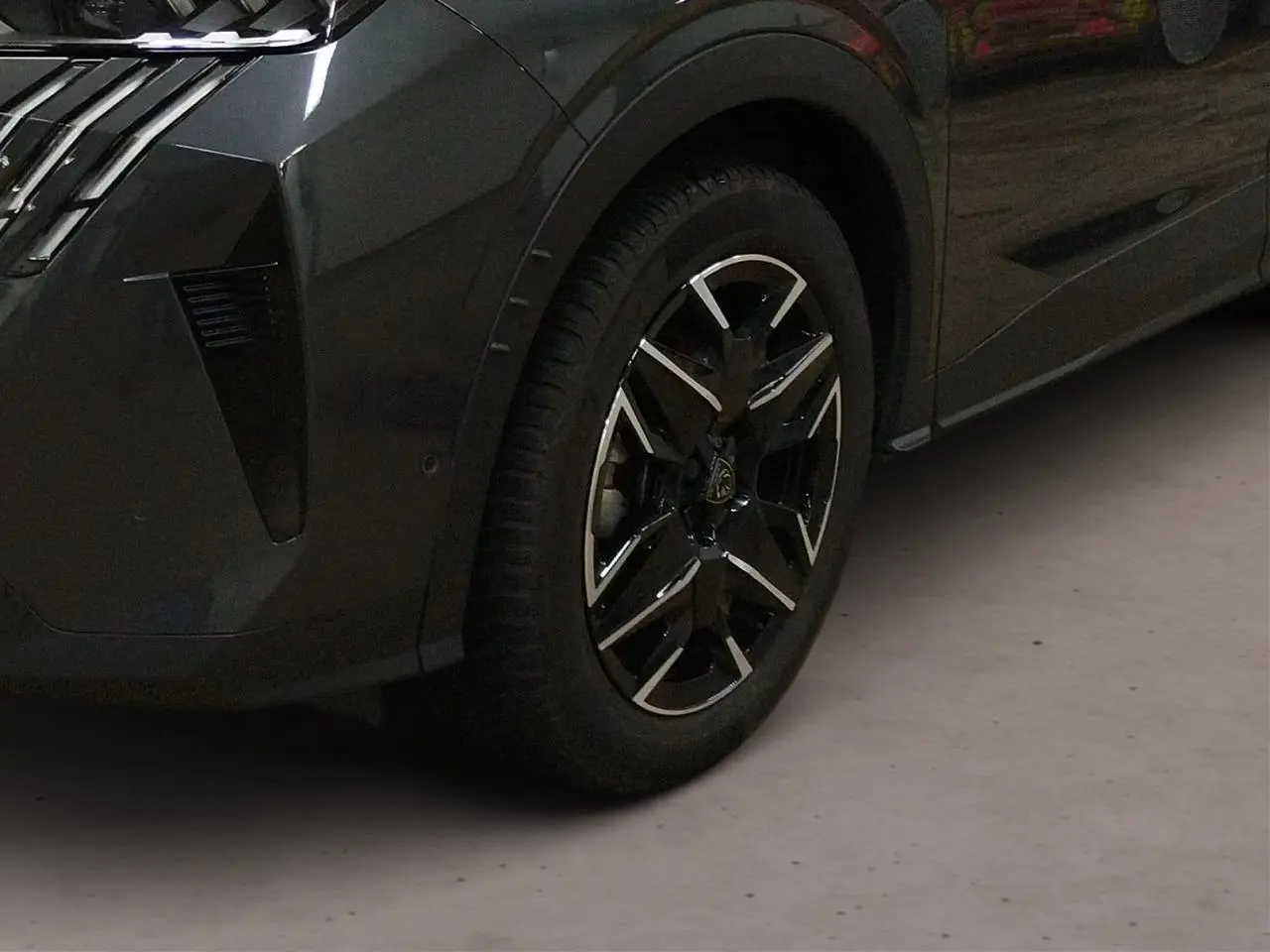 Gros plan sur la roue avant gauche du Peugeot 3008 Hybrid gris Titane avec jante alliage noire et argentée.