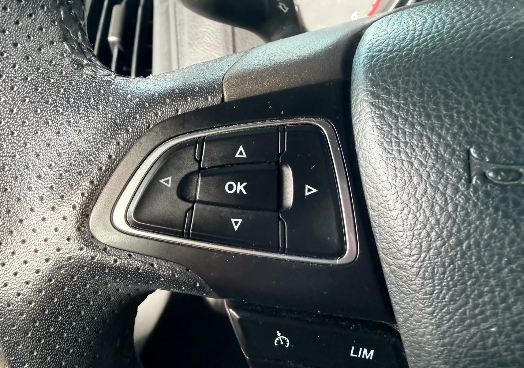 Vue intérieure du coffre ouvert d'une Ford Focus gris, montrant un espace de rangement vide avec un triangle de signalisation rouge fixé sur le côté droit.