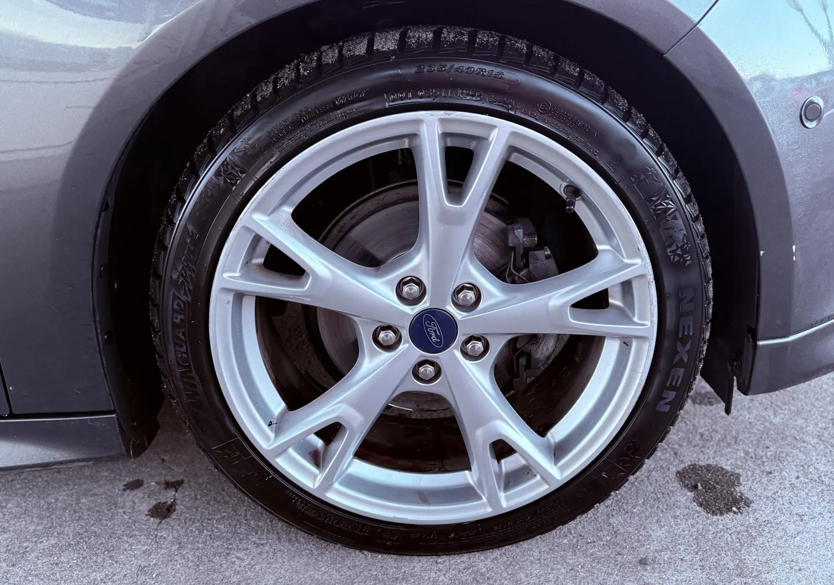 Gros plan sur la jante alliage argentée et pneu Nexen du côté avant gauche d'une Ford Focus grise 2018.