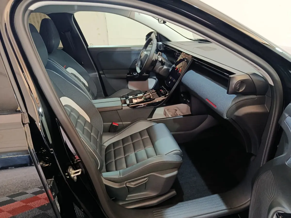 Intérieur avant côté gauche de la Citroën C5 Hybride noire 2026 avec sièges cuir et grand écran tactile central.