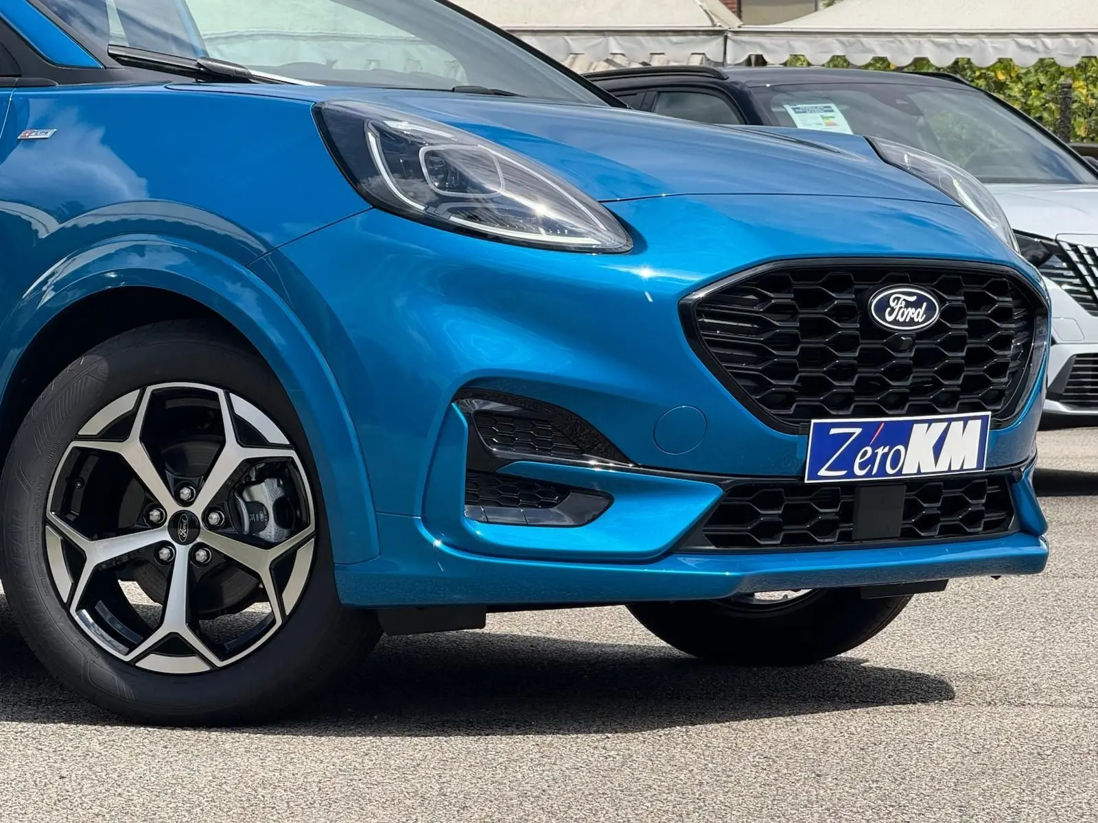 Vue de 3/4 avant droit d'une Ford Puma 2025 bleu Aqua avec calandre noire et jantes alliage distinctives.