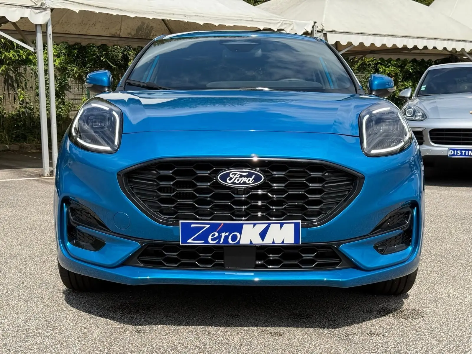 Vue frontale d'une Ford Puma 2025 en bleu aqua, avec calandre noire hexagonale et phares LED distinctifs.