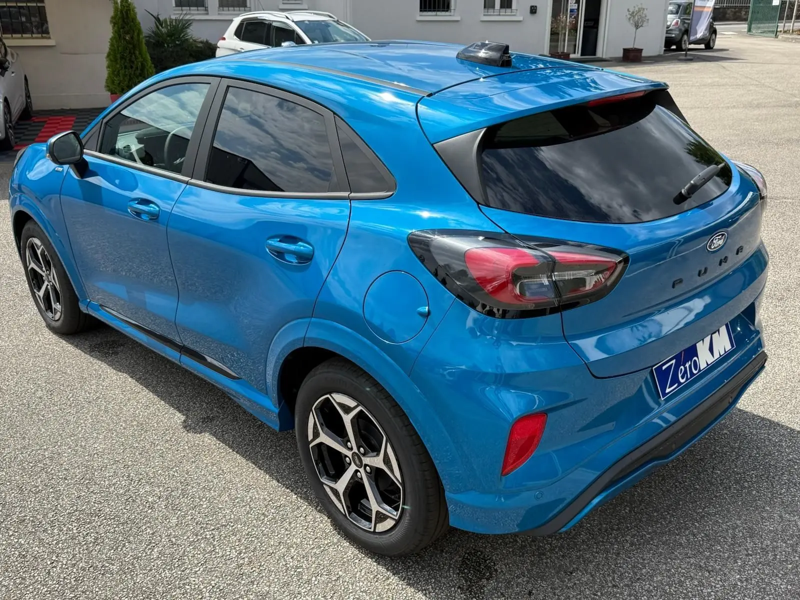 Ford Puma 2025 bleu Aqua en vue 3/4 arrière droit, avec feux arrière fumés et jantes alliage noires.