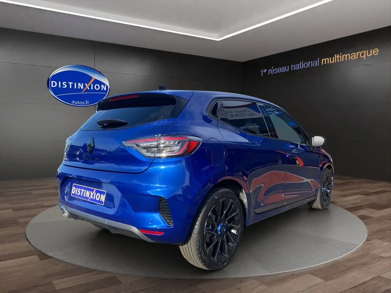 Vue 3/4 arrière droite d'une Renault Clio V TCE 90 Esprit Alpine bleu Iron avec jantes noires en showroom.