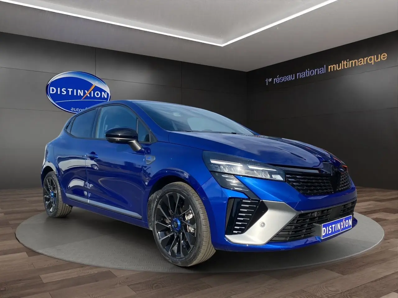 Renault Clio V TCE 90 Esprit Alpine bleu Iron en 3/4 avant droit, jantes noires et détails sportifs visibles.