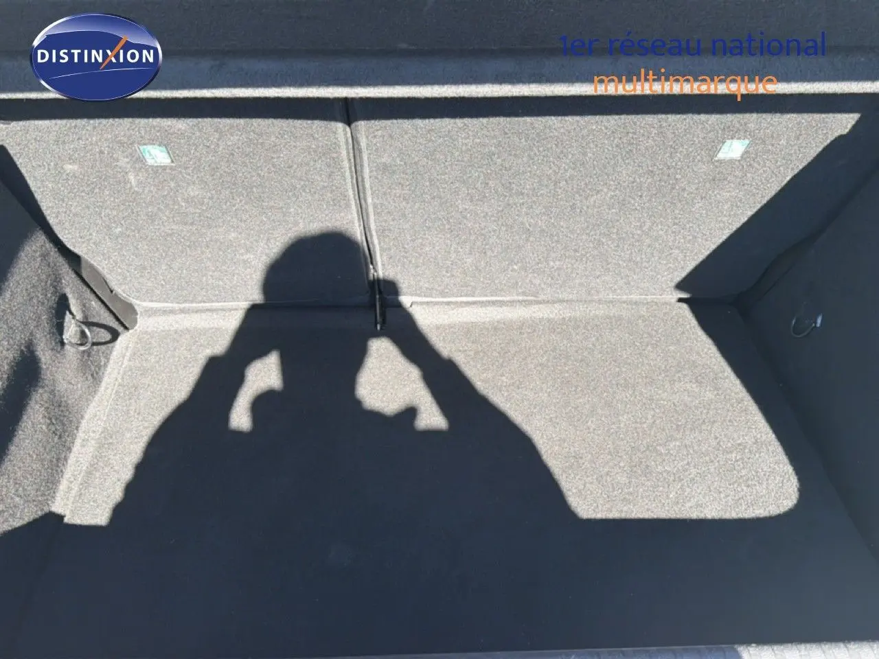 Coffre vide de la Renault Clio blanche 2025, vue de dessus montrant la moquette grise et les fixations internes.