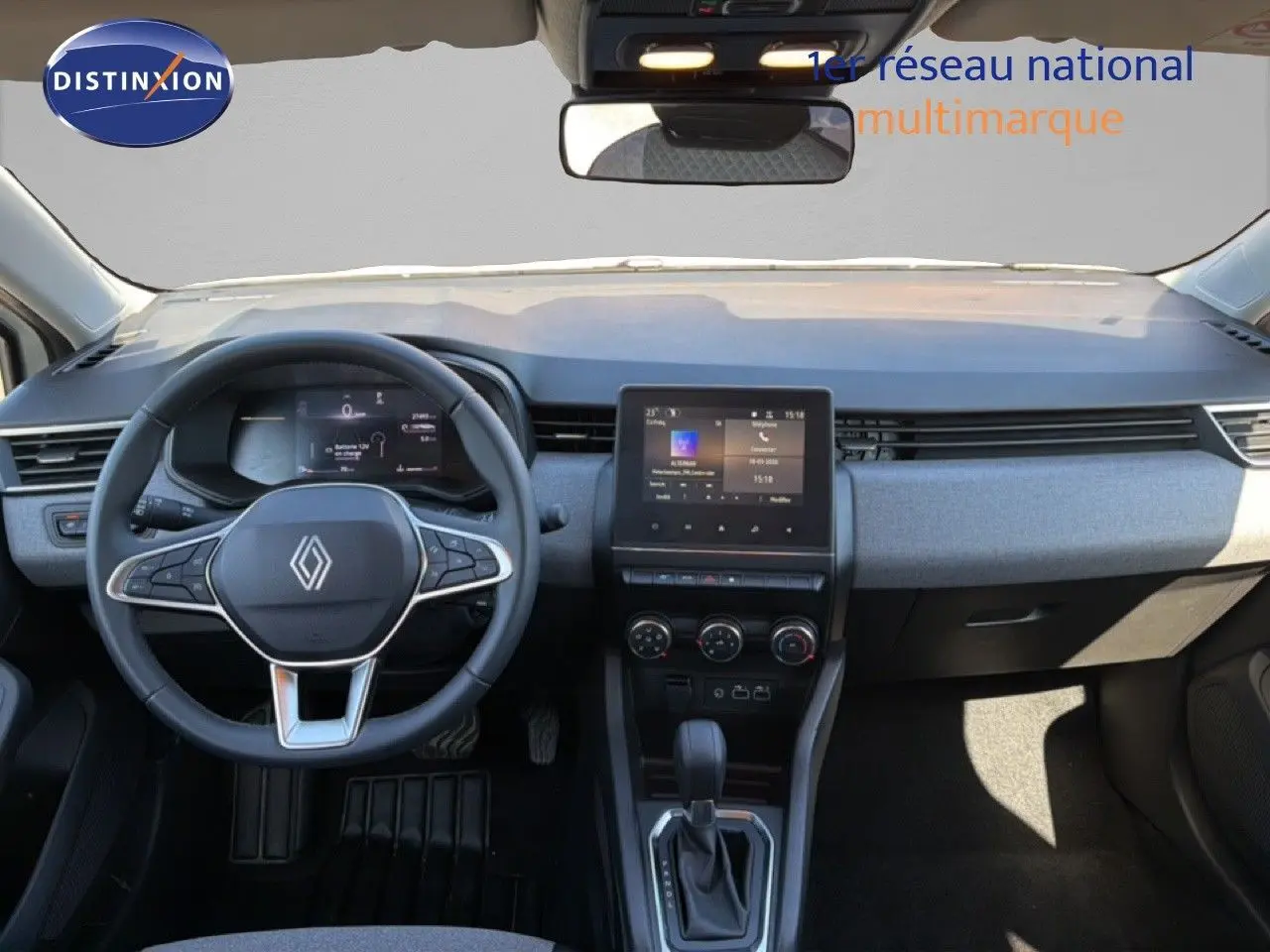Vue intérieure frontale du tableau de bord de la Renault Clio blanche 2025 avec écran tactile et volant multifonction.
