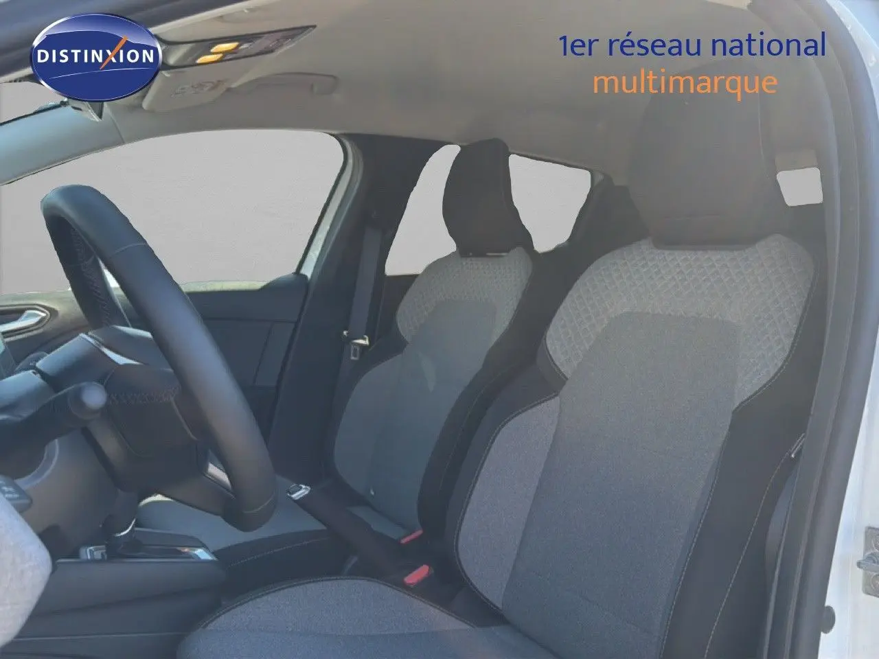 Vue intérieure côté conducteur de la Renault Clio blanche 2025, sièges tissu gris avec détails noirs et volant cuir multifonction.