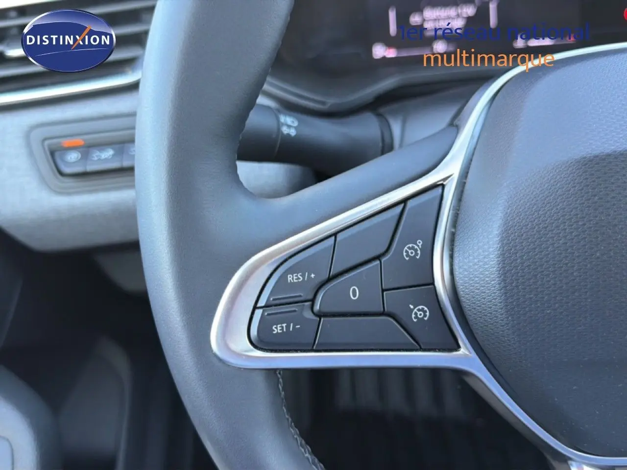 Gros plan sur les commandes au volant côté gauche d'une Renault Clio blanche, version 2025, avec finition noire.