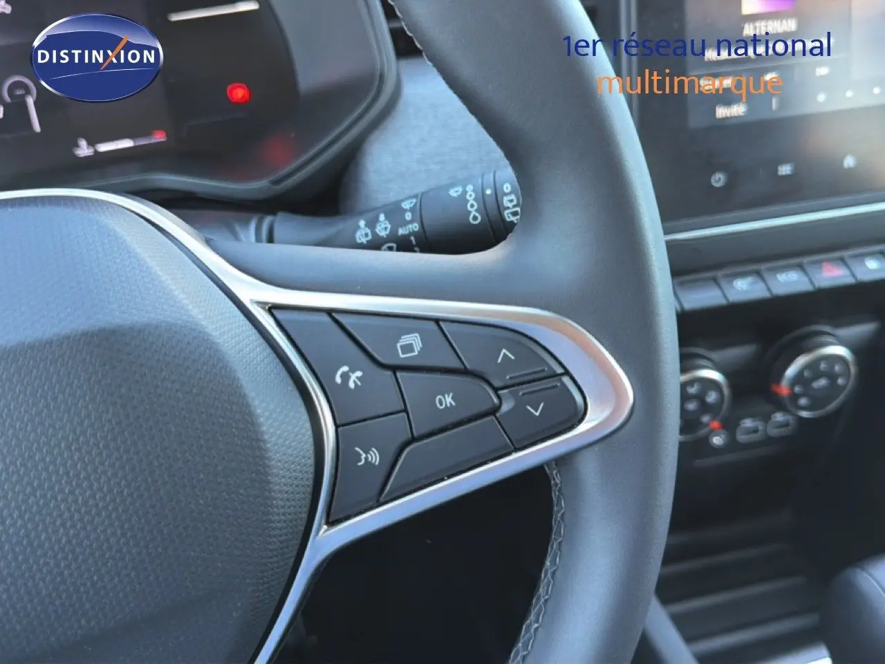 Gros plan sur le volant multifonction en cuir noir de la Renault Clio 2025, avec commandes intégrées et tableau de bord partiel.