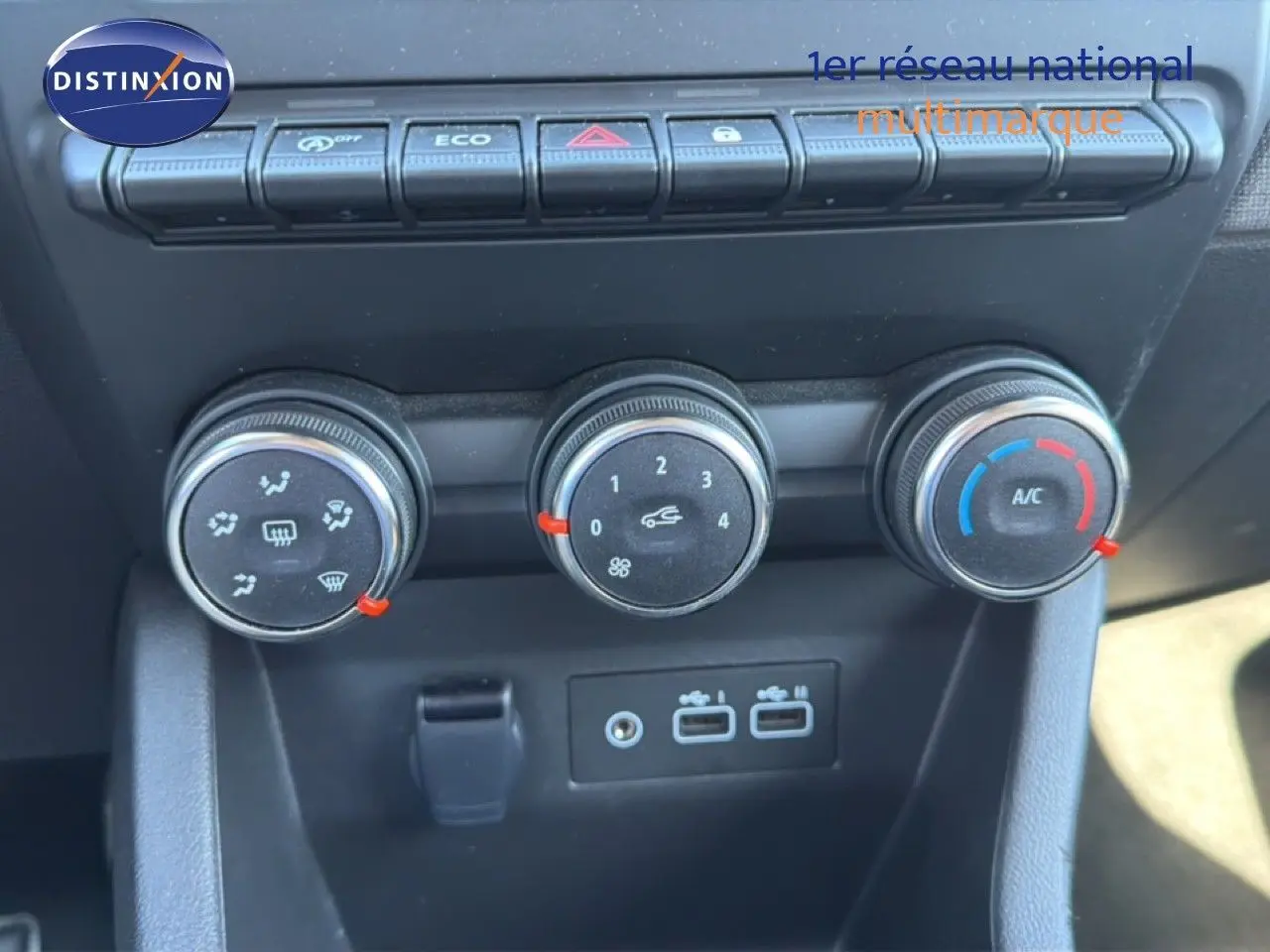 Gros plan sur les commandes de climatisation et les ports USB du tableau de bord d’une Renault Clio blanche 2025.